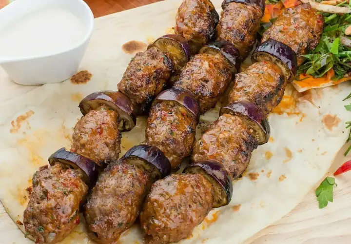 Grillowane szaszłyki z mielonego mięsa i bakłażana, czyli pyszna kofta libańska, podane na chlebku z sosem.