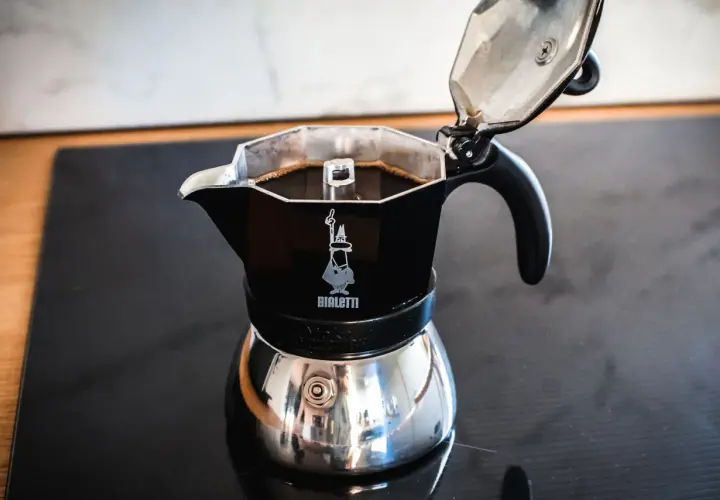 Czarna kawiarka Bialetti z gotową kawą na kuchence. Idealna instrukcja, jak parzyć kawę w kawiarce.