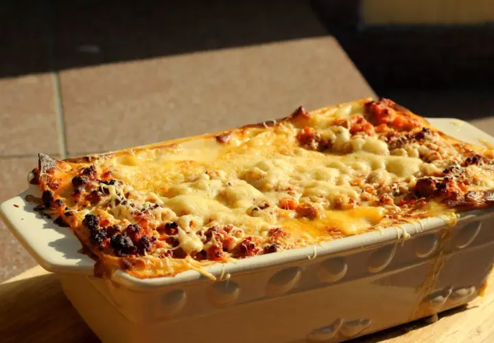 Gorąca, zapieczona lasagne orzepis w naczyniu, z ciągnącym się serem i rumianymi brzegami.
