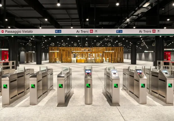 Cancelli automatici di una moderna stazione metro a Roma, con indicazioni per le fermate e i treni.