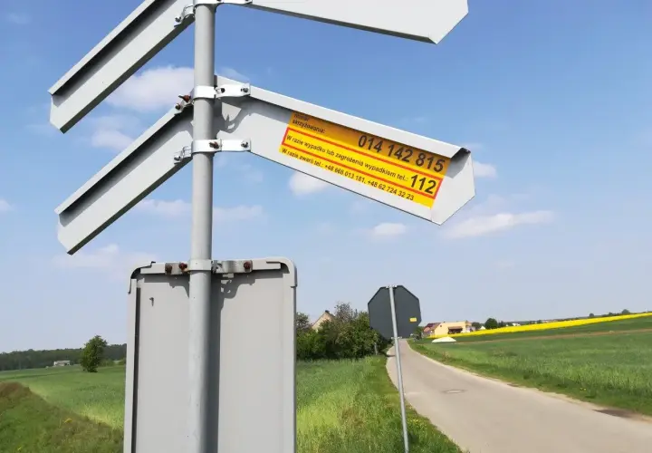 Znak informuje o numerze skrzyżowania i numerach alarmowych w razie wypadku lub awarii na przejeździe kolejowym.