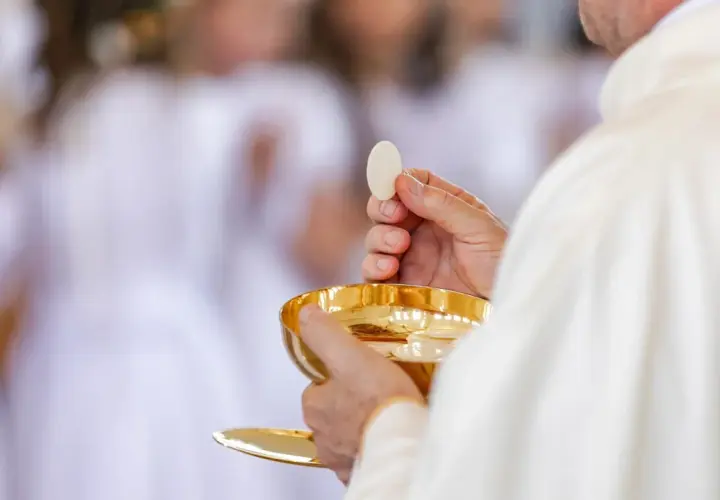 Ksiądz trzymający hostię i kielich podczas komunii świętej.