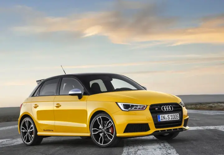 Żółty Audi RS1 z czarnym dachem i felgami, gotowy do jazdy po pustej drodze o zachodzie słońca.