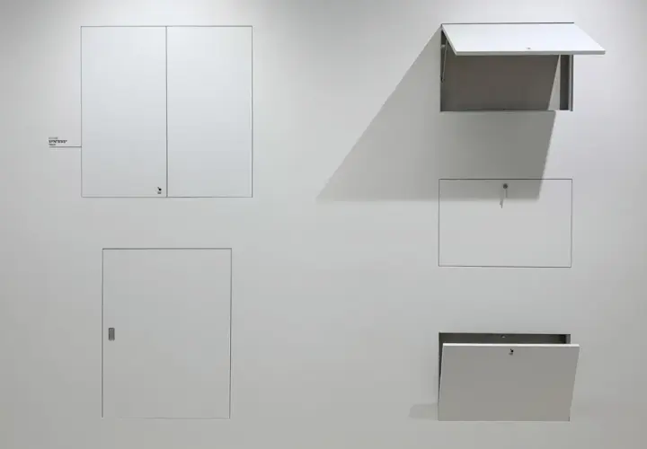 Botole cartongesso invisibili filo muro, integrate perfettamente nella parete bianca, alcune aperte, altre chiuse, nascondono accessi segreti.
