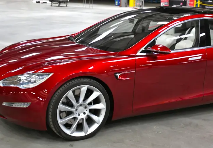 Czerwony Tesla, który mąż nie chce dać mi samochodu, lśni w słońcu.