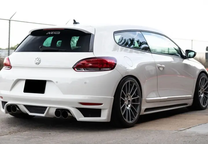 La parte posteriore di una Volkswagen Scirocco bianca, con un diffusore sportivo e quattro scarichi.