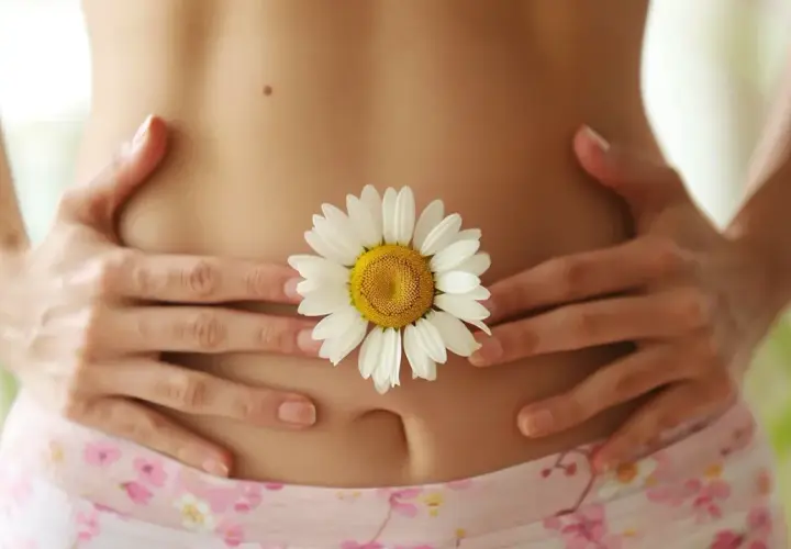 Delikatny brzuch z kwiatem rumianku, symbolizującym naturalne sposoby na biegunke.