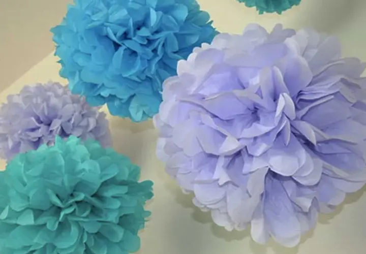 Pompones de papel pinocho en tonos azules y lilas, perfectos para manualidades decorativas.