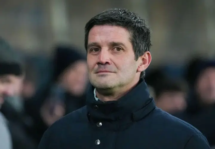Mężczyzna w ciemnej kurtce, z siwiejącymi włosami, wygląda jak inter trener podczas meczu.