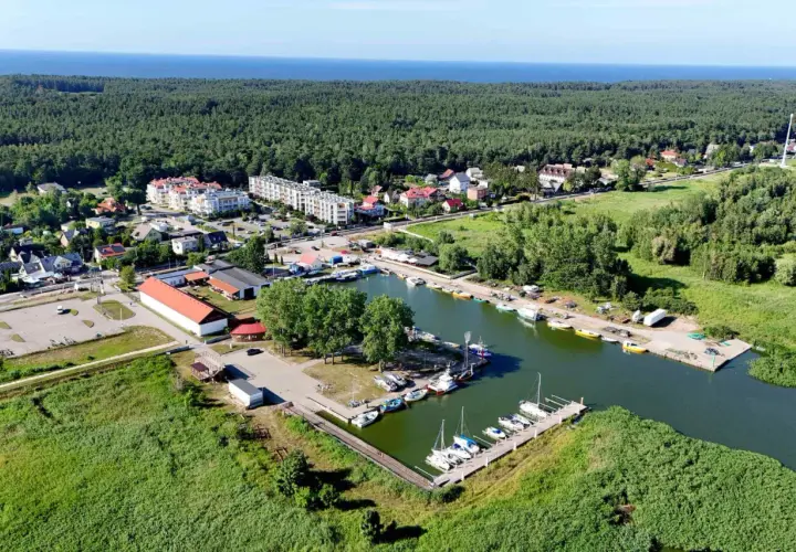 Widok na przystań jachtową i zabudowania w otoczeniu zieleni, idealne miejsce na camping Mierzeja Wiślana.