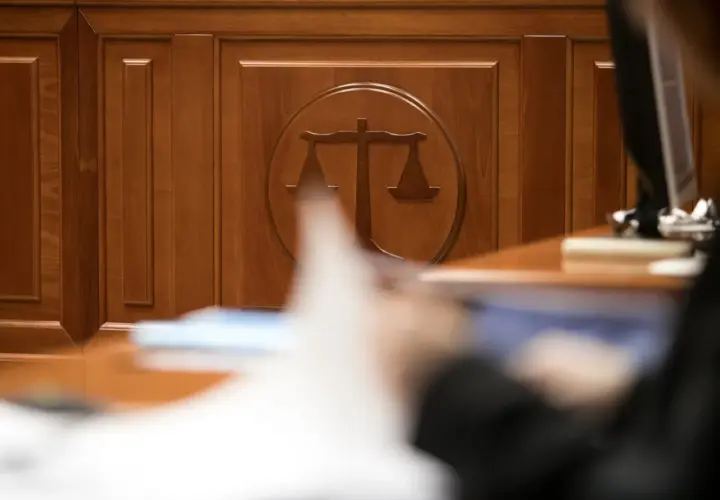 Drewniana ściana z symbolem wagi sprawiedliwości. Zastanawiasz się, ile trwa sprawa w sądzie cywilnym? Czas oczekiwania bywa różny.