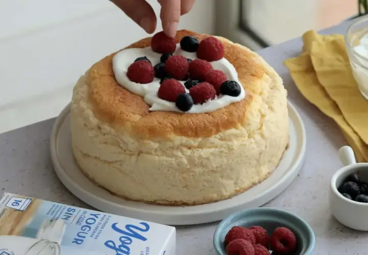 Deliciosa tarta de yogur griego esponjosa, decorada con frambuesas y arándanos frescos.