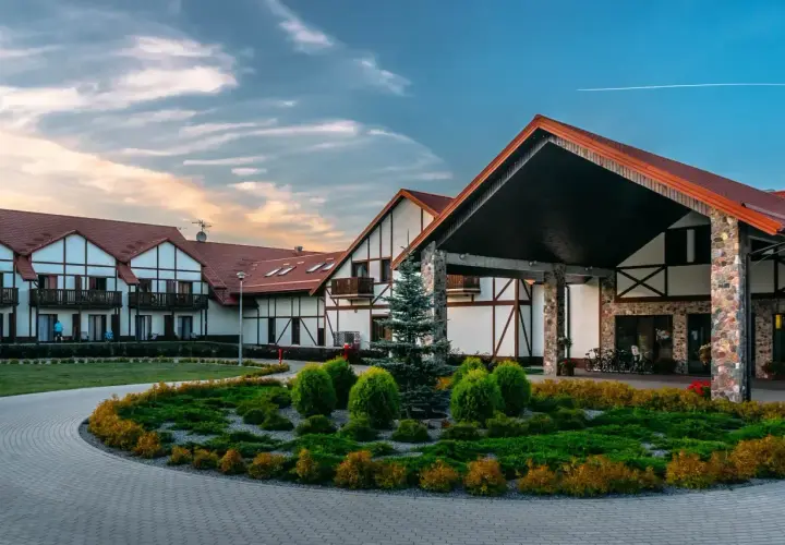 Hotel Mikołajki Leisure & Spa zaprasza do wypoczynku. Piękny budynek z kamiennymi elementami i zadbanym ogrodem.