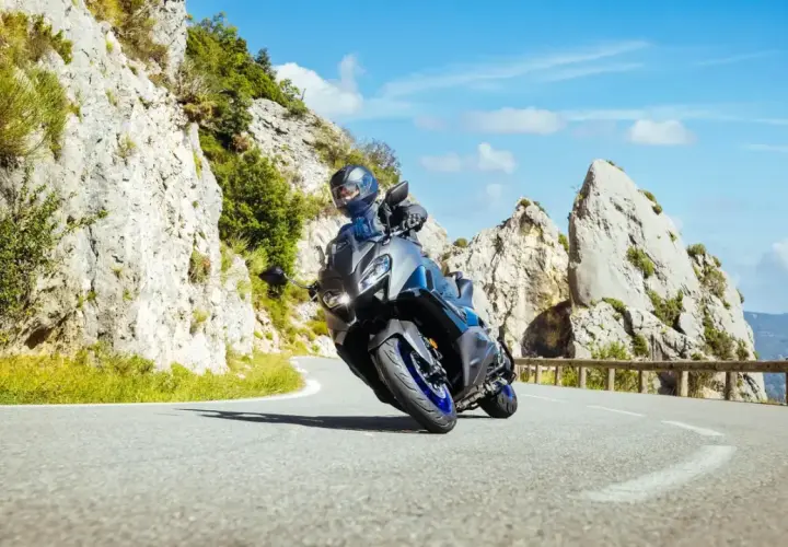 Motocyklista na sportowym motocyklu z power commanderem pokonuje zakręt na górskiej drodze, otoczony skalistymi zboczami i błękitnym niebem.