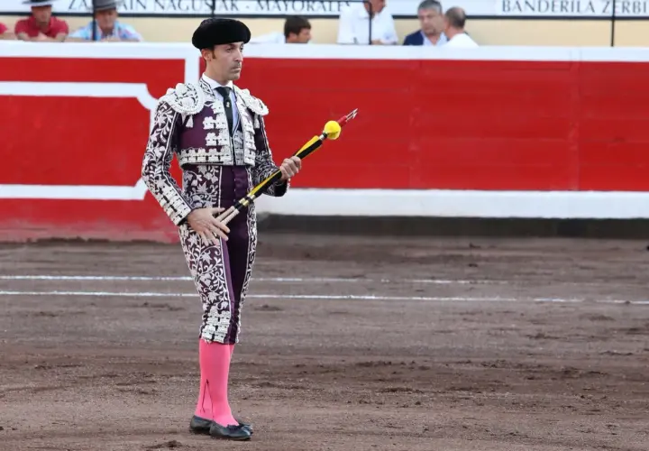Torero español con traje de luces morado y blanco, listo para clavar banderillas.