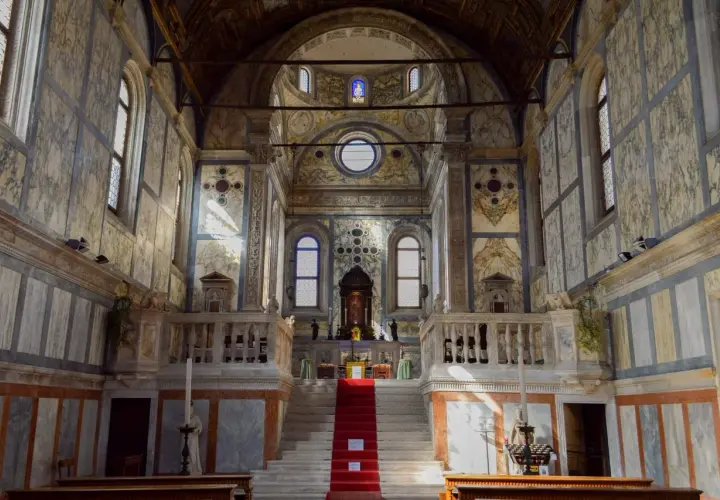 Intérieur de l'église Santa Maria dei Miracoli à Venise, avec son escalier rouge menant à l'autel, le tout orné de marbre.