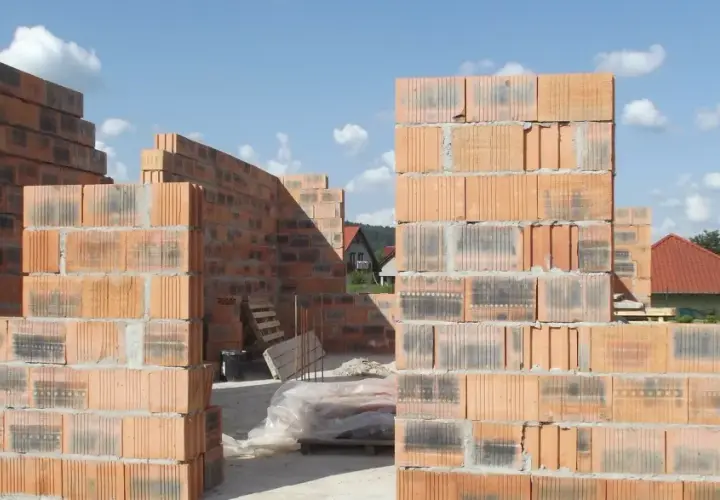 Budowa domu z pustaków ceramicznych. Widać ściany wznoszone z cegieł, które mają różne wymiary, tworząc konstrukcję.