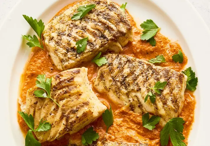 Filetes de bacalao a la parrilla con salsa de pimientos rojos y perejil fresco. Un plato principal perfecto para tus recetas de bacalao.