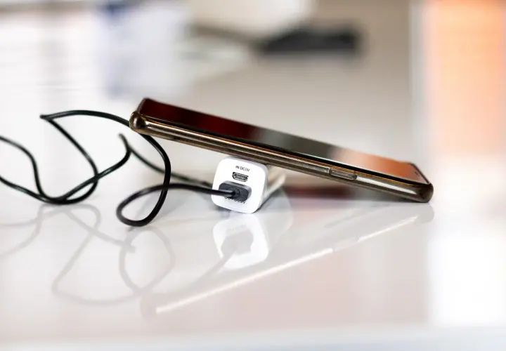 Smartfon podłączony do ładowarki, by zapobiec nadmiernemu zużyciu baterii.