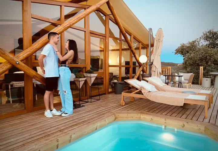 Pareja disfrutando de la tranquilidad de la dehesa experiences, con piscina y tumbonas en una cabaña de madera.