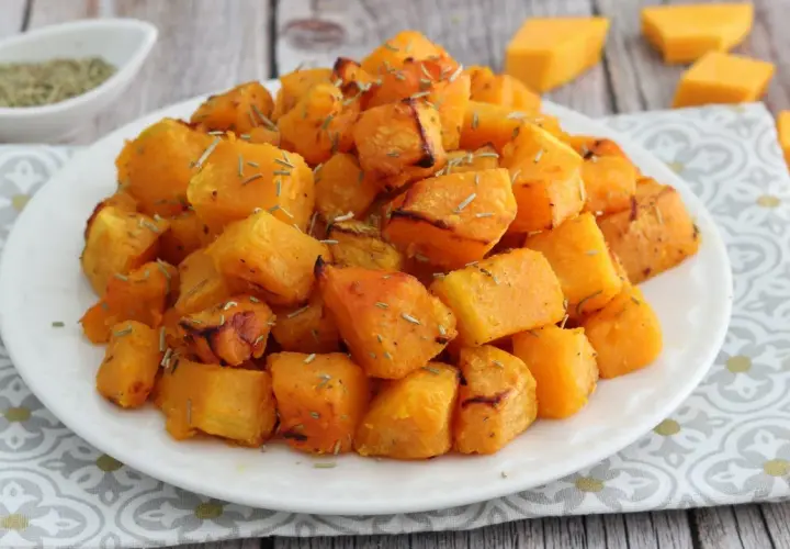 Zucca in friggitrice ad aria, dorata e profumata, servita su un piatto bianco con erbe aromatiche.