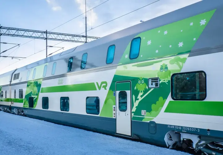 Ein moderner Doppelstockzug der VR in Finnland, verziert mit Eulen und Sternen, fährt durch eine verschneite Landschaft.