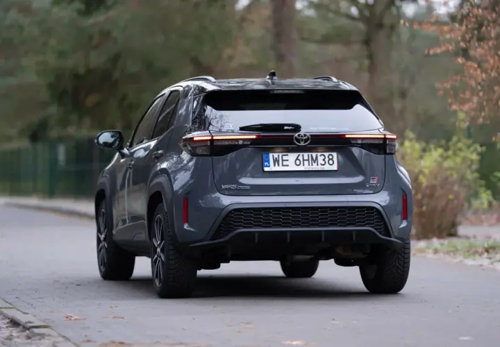 Szary Toyota Yaris Cross hybrydowy z tyłu na drodze.