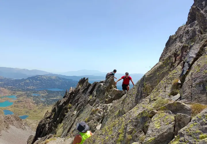Trepando por rocas, un pic carlit con lagos turquesas de fondo.