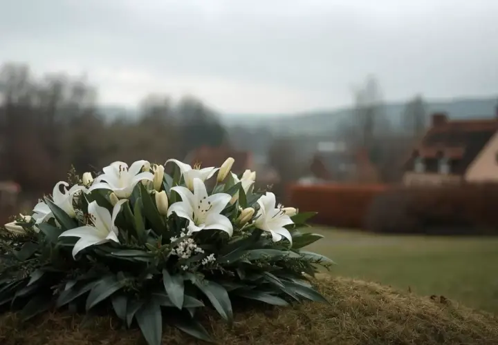 Białe lilie na tle wiejskiego krajobrazu. Wieniec pogrzebowy symbolizuje pamięć i szacunek, a zasiłek pogrzebowy KRUS pomaga w trudnych chwilach.