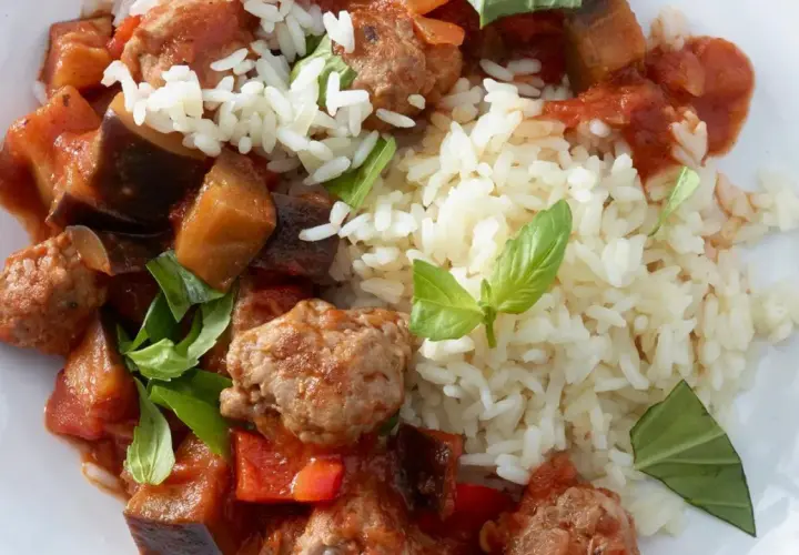 Herzhafte Salsiccia-Zubereitung in der Pfanne mit Auberginen, Paprika und Reis, garniert mit frischem Basilikum.