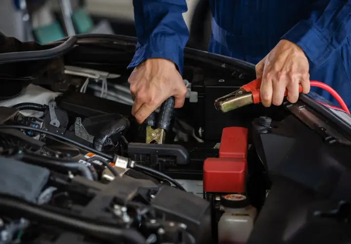 Mekaniker kopplar startkablar för att ladda nytt bilbatteri.