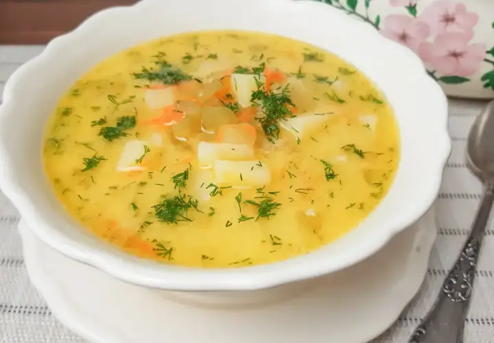 Aromaticzna zupa ogórkowa z ziemniakami i marchewką, posypana świeżym koperkiem. Idealna na chłodne dni.