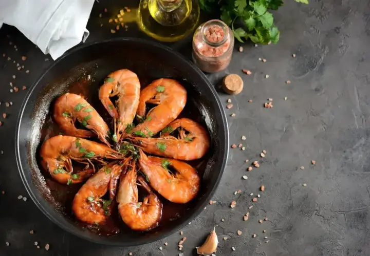 Pyszne krewetki w sosie, część dania frutti di mare, skropione natką pietruszki, gotowe do podania.