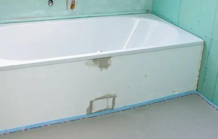 Badewanne in einem Rohbau. Die Anschlussfugen abdichten ist der nächste Schritt, bevor die Fliesen verlegt werden.