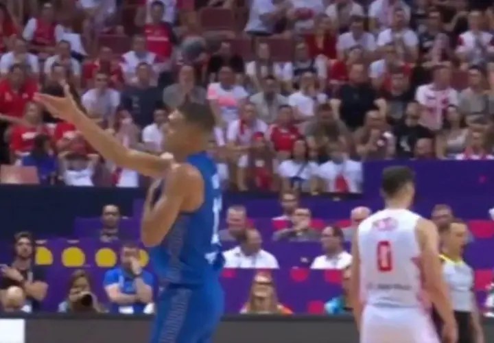 Koszykarz w niebieskim stroju gestykuluje na tle trybun, gdzie widać kibiców w biało-czerwonych barwach. Mecz Izrael Polska.