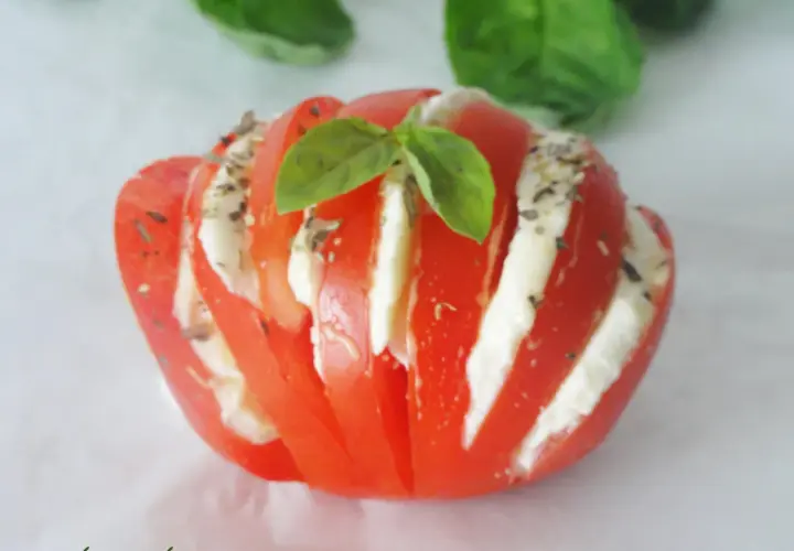 Tomate farcie d'une délicieuse recette avec mozzarella, garnie de basilic frais et d'herbes. Une bouchée d'été parfaite.