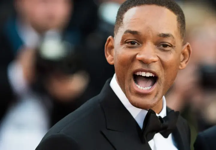 Will Smith w czarnym smokingu z muszką, uśmiecha się szeroko. Ciekawe, ile lat ma Will Smith, patrząc na jego energię!
