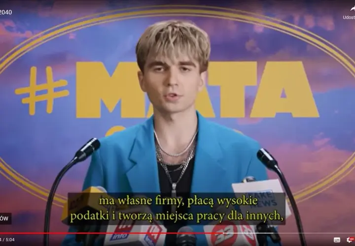 Młody mężczyzna w niebieskiej marynarce, z hasłem #MATA na tle. Mówi o firmach, podatkach i tworzeniu miejsc pracy.