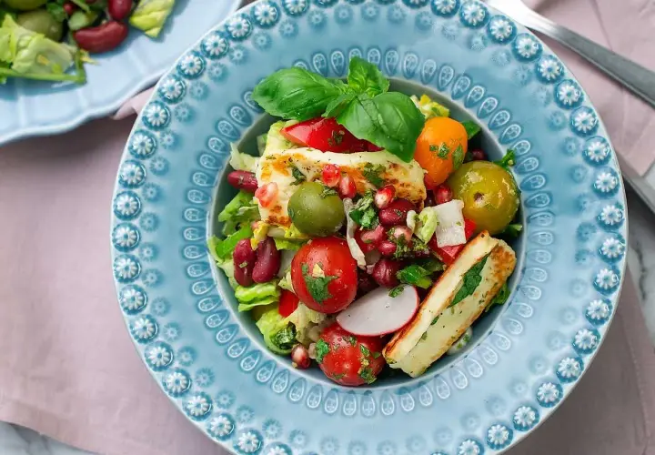 En färgstark sallad med grillad halloumi, tomater, oliver, bönor och granatäpple. Ett perfekt sallad recept för en lätt lunch.