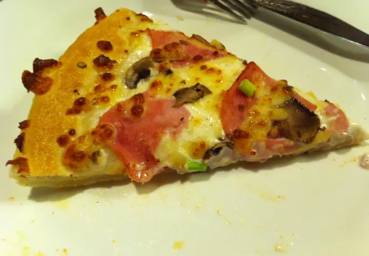 Kawałek pizzy z szynką i pieczarkami, idealny na festiwal pizzy, który trwa do jutra.