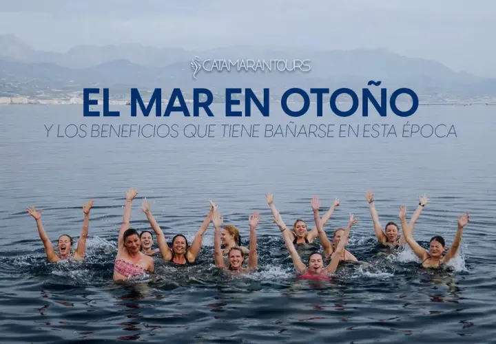 Grupo de personas nadando en el mar con los brazos en alto, disfrutando de los beneficios de bañarse en otoño.