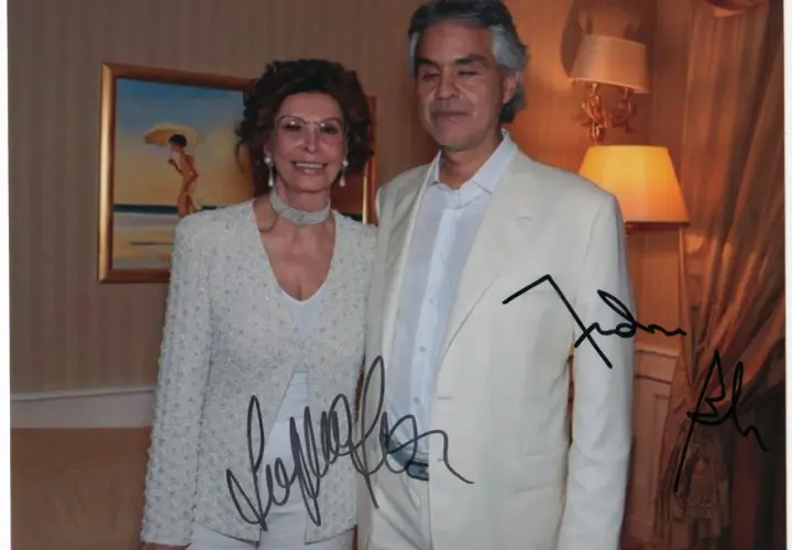 Sophia Loren and Andrea Bocelli pose for a photo, both with autographs on the image.