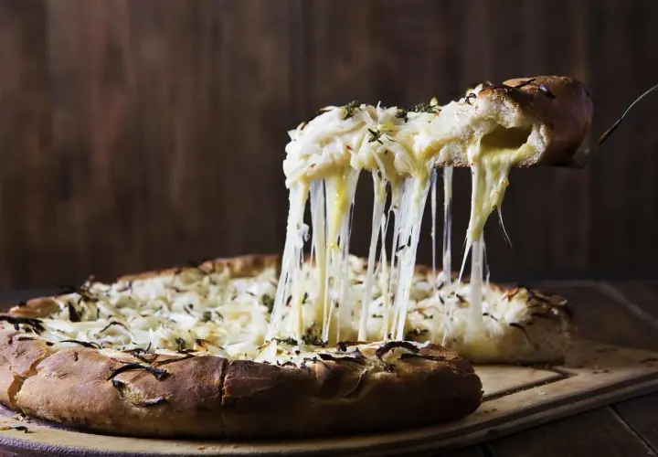 Rozpływający się ser ciągnie się z kawałka pizzy quattro formaggi, tworząc apetyczny widok.
