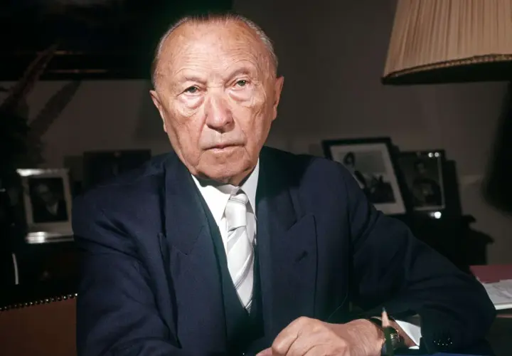 Konrad Adenauer, der von 1949 bis 1963 Bundeskanzler der Bundesrepublik Deutschland war, sitzt im Anzug am Schreibtisch.