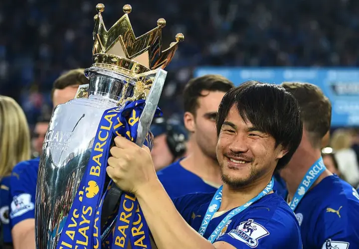Shinji Okazaki z pucharem Premier League, uśmiechnięty, świętuje zwycięstwo.