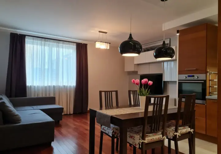 Nowoczesny salon z jadalnią, kanapą, stołem i kwiatami.