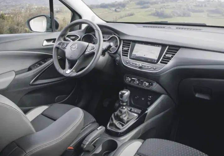 Interior del Opel Crossland X con asientos grises y negros, volante multifunción y pantalla táctil.