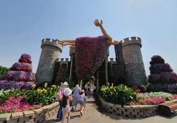 Niesamowity **Miracle Garden w Dubaju** zachwyca kwitnącą rzeźbą człowieka na tle zamku. Kolorowe kwiaty tworzą bajkową scenerię.