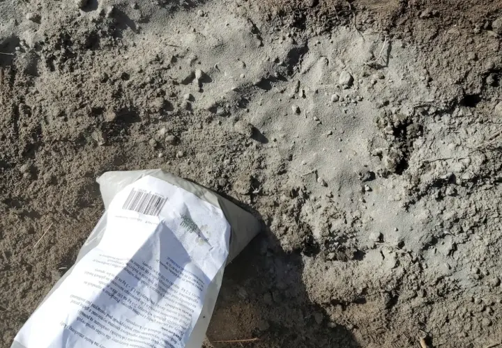 Opakowanie mączki bazaltowej leży na ziemi. Czy mączka bazaltowa jest szkodliwa? To naturalny nawóz, który poprawia strukturę gleby i dostarcza minerałów.