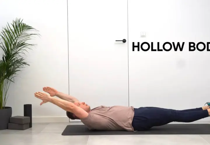 Mężczyzna leży na macie, wykonując ćwiczenie hollow body. Ręce wyciągnięte nad głowę, nogi uniesione.